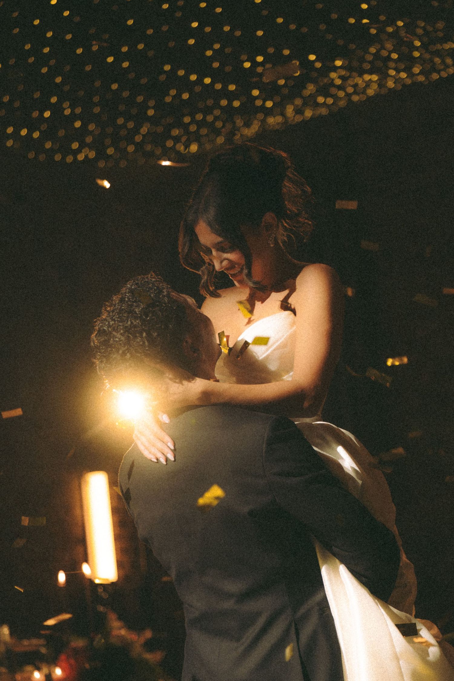Bride and groom share a romantic first dance embrace under twinkling ceiling lights at their wedding reception.