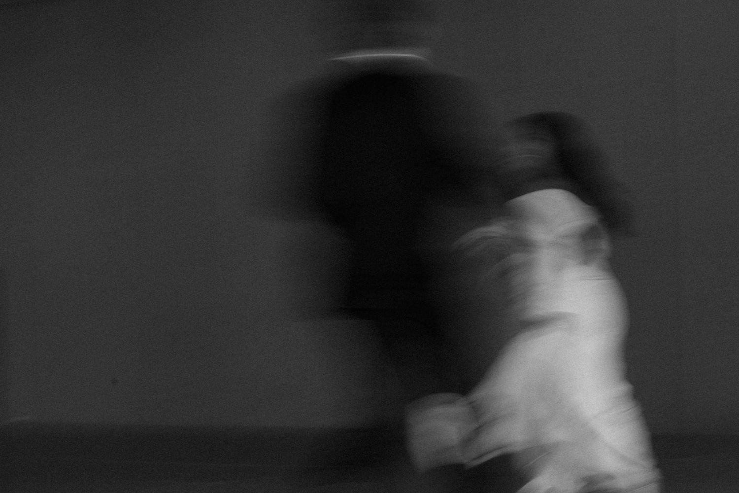 Blurry black and white photo of two figures in motion, creating an abstract ghostly effect.