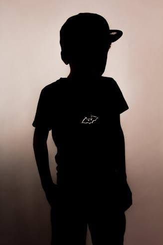 Silhouette of a child wearing a baseball cap and t-shirt with small logo, posed against a light background.