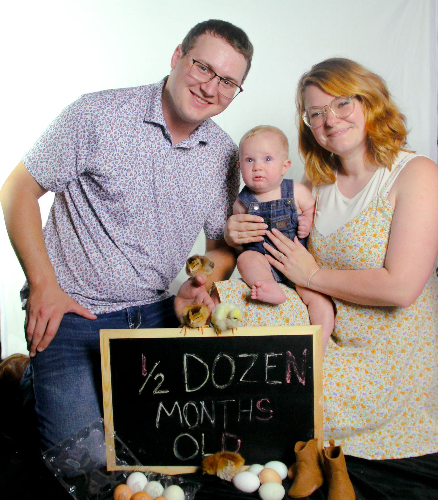 Family of three celebrating baby's half dozen months milestone with chicks and eggs in a cheerful photo.