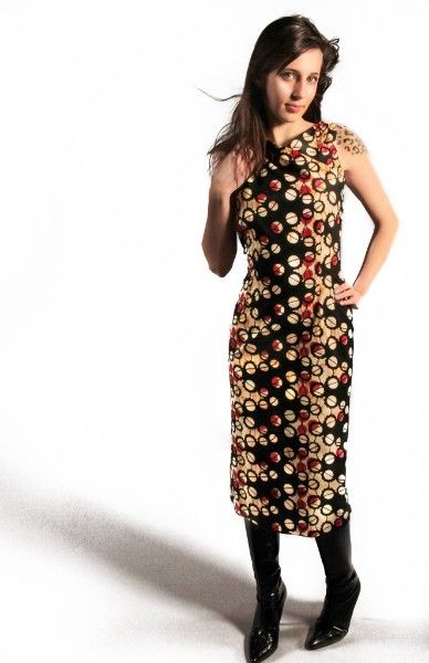 Woman modeling a sleeveless midi dress with colorful circle print pattern, paired with black knee-high boots.