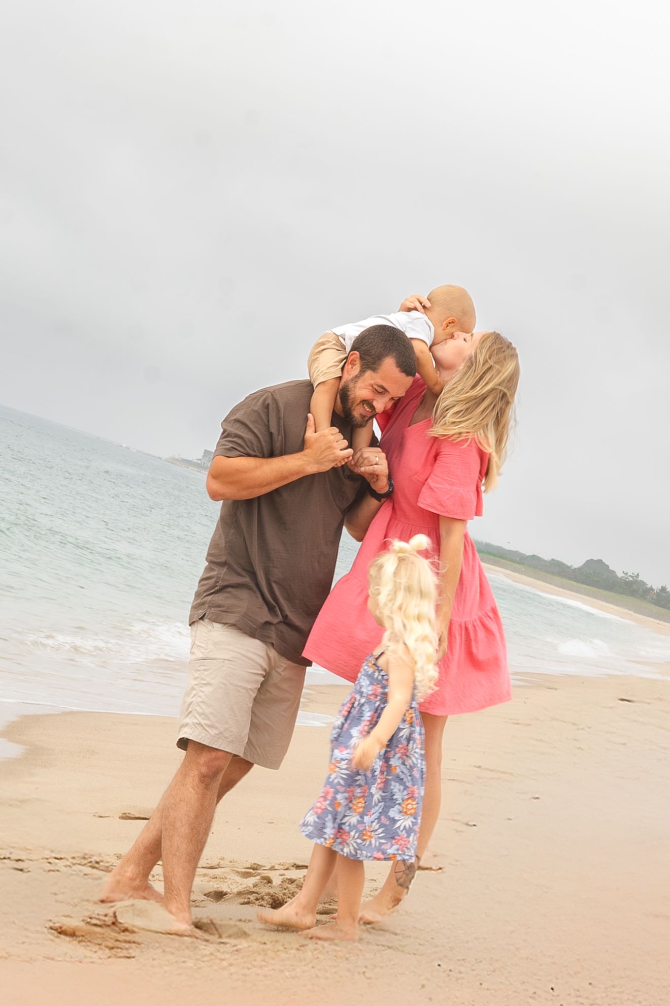 Happy family with two young children sharing a joyful moment together on a sandy beach.