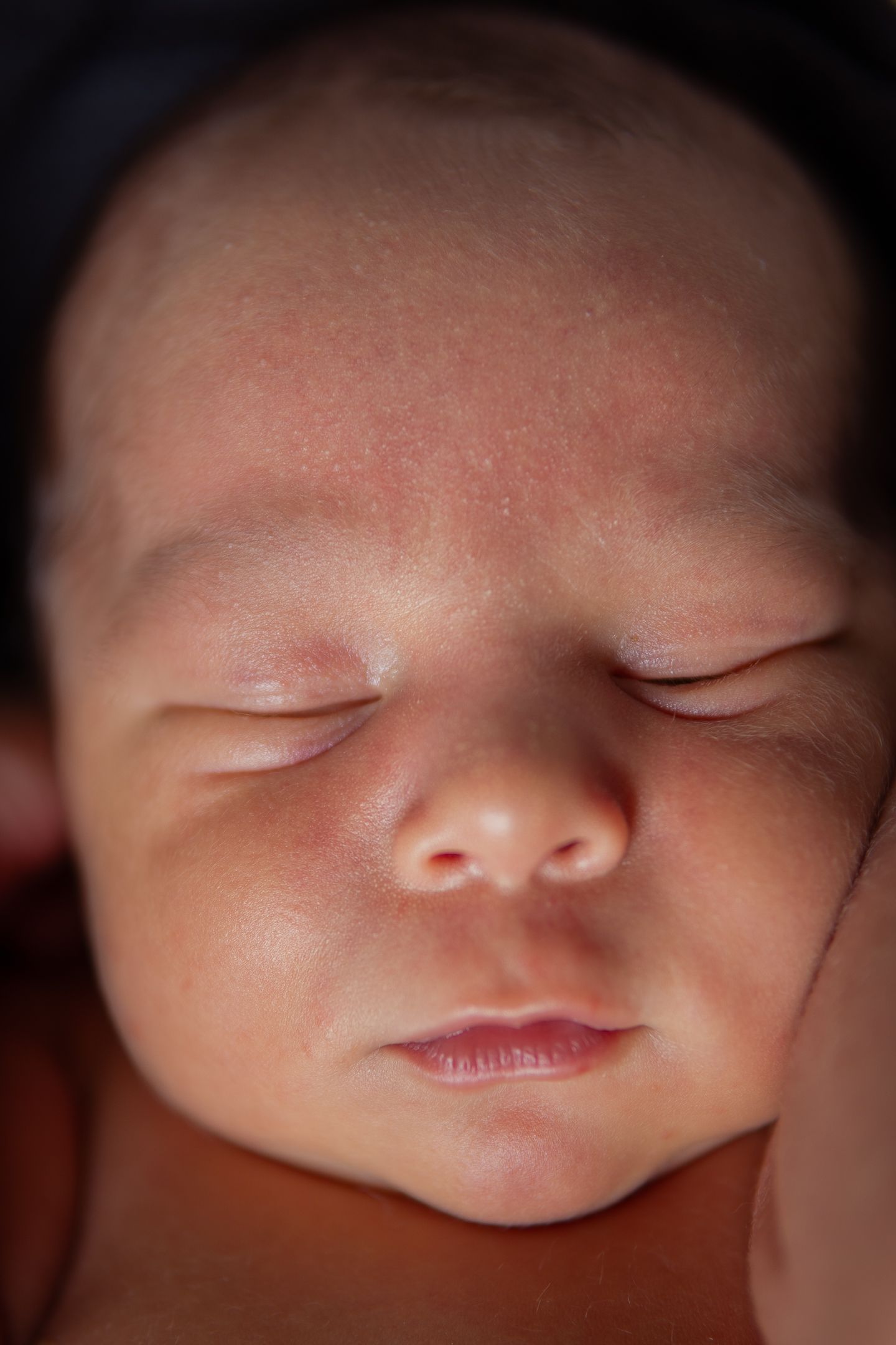 Close-up macro shots of a sleeping baby's peaceful face against dark background.
