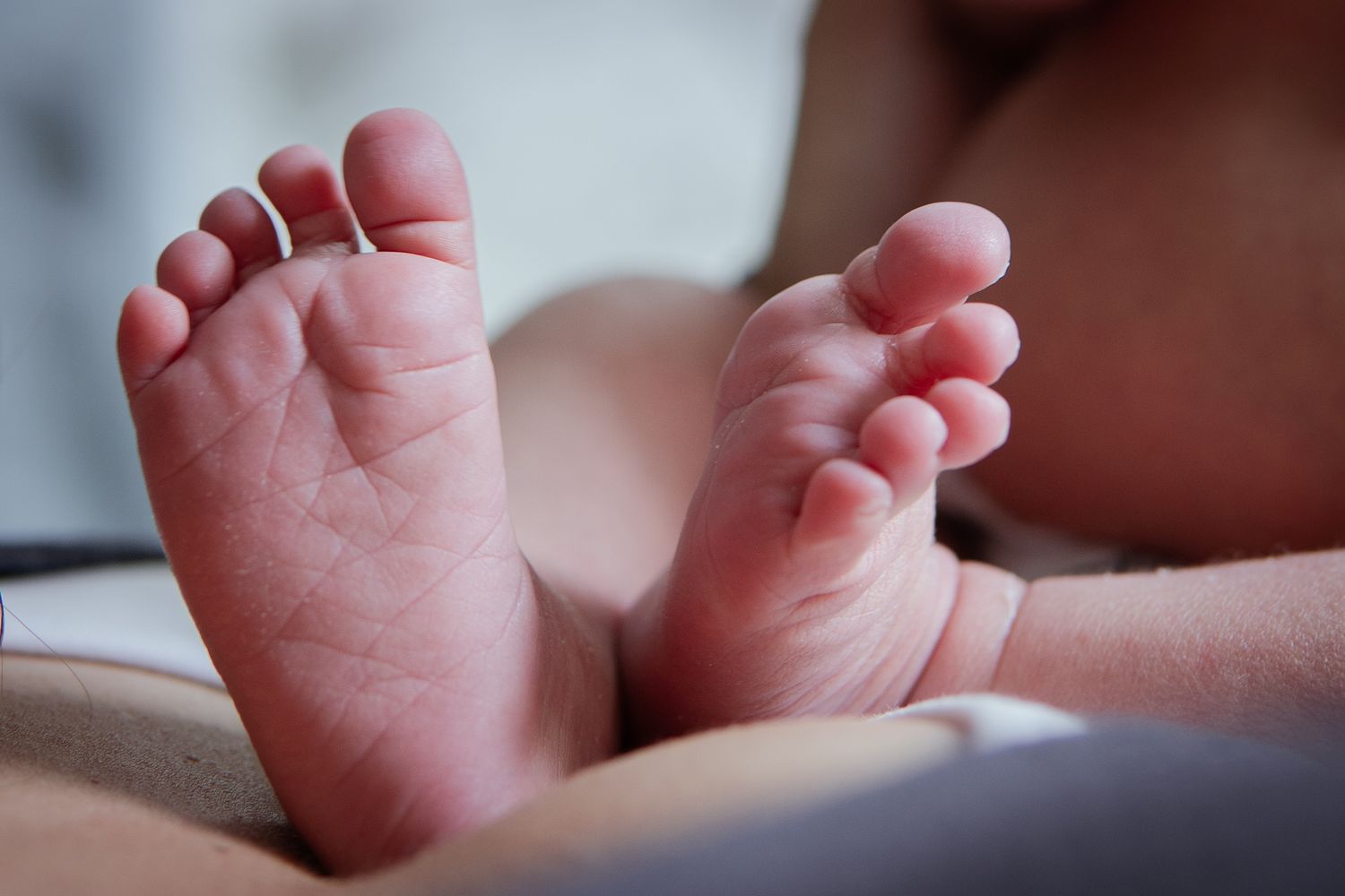 Close-up of tiny newborn baby feet showing delicate pink skin and toes.