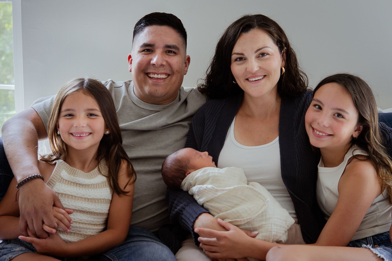 Happy family portrait series with parents and children gathered around newborn baby.