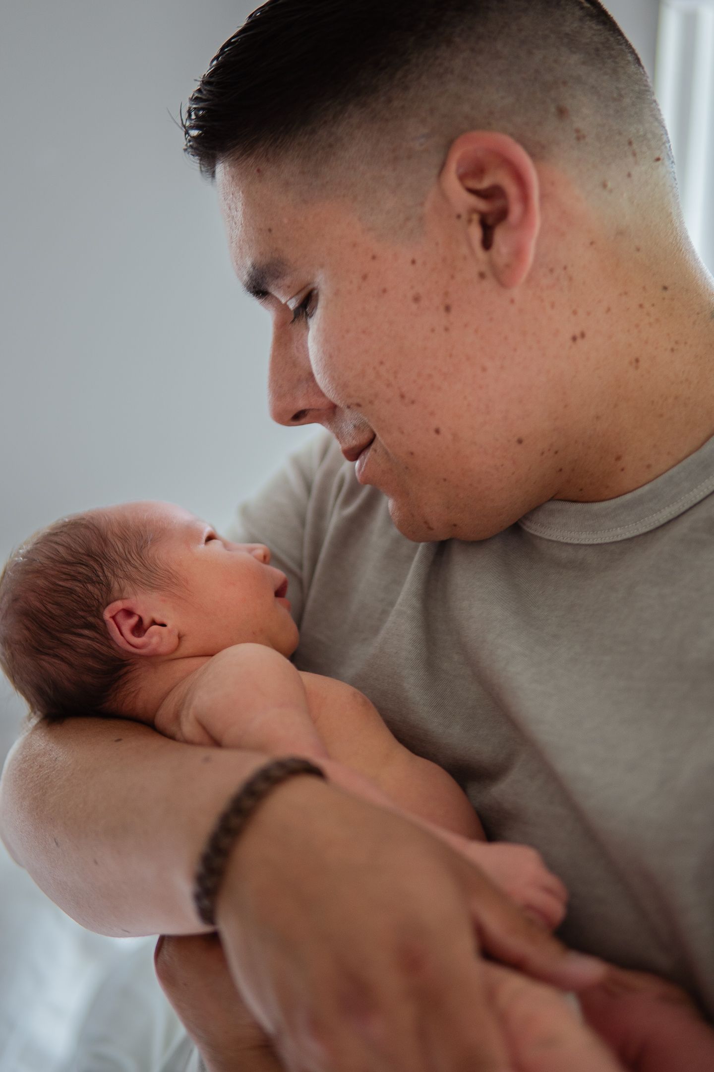 Tender moments between a baby and caregiver in casual grey attire.