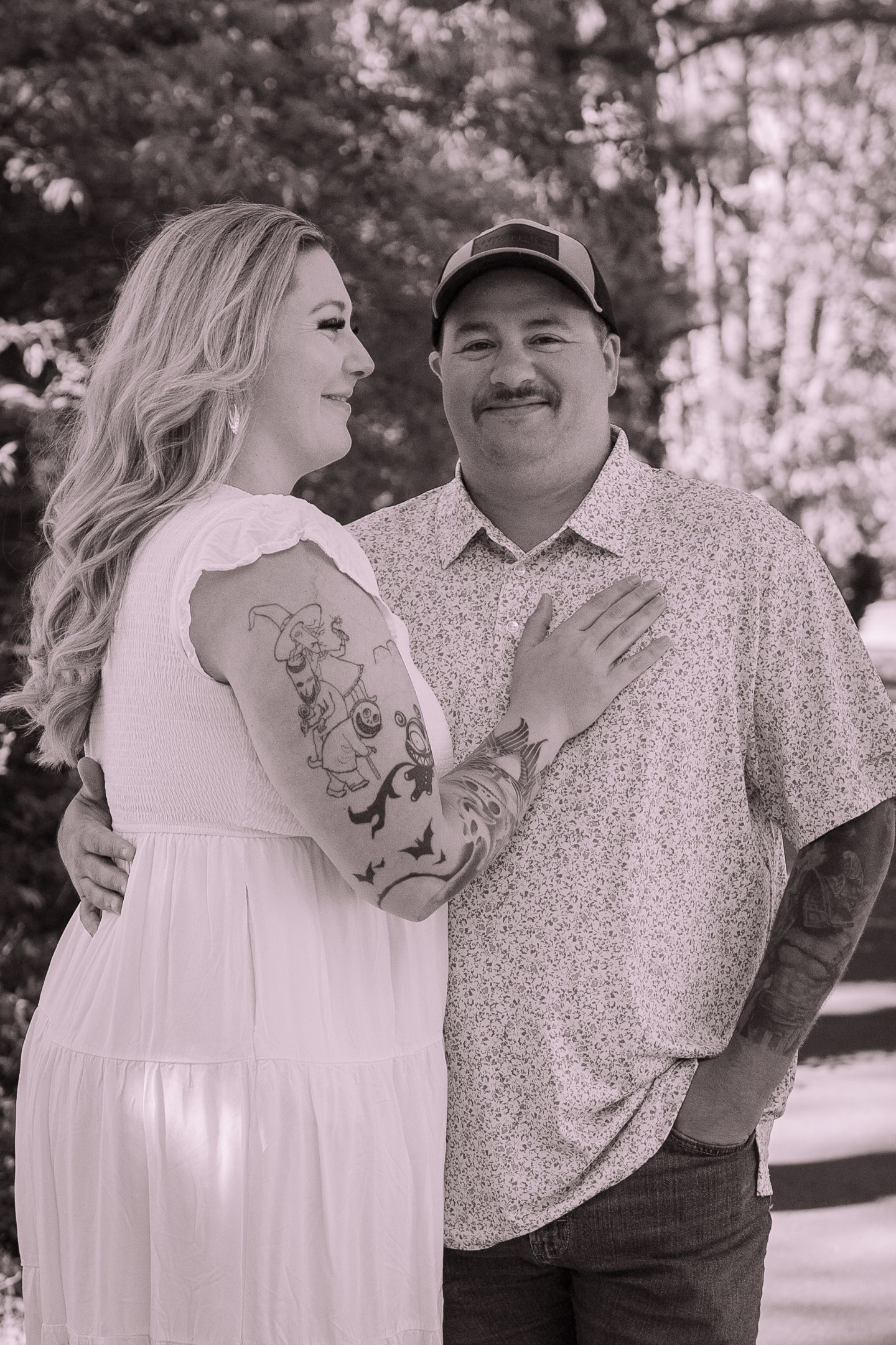 Black and white portrait showing a tender moment between two people outdoors.