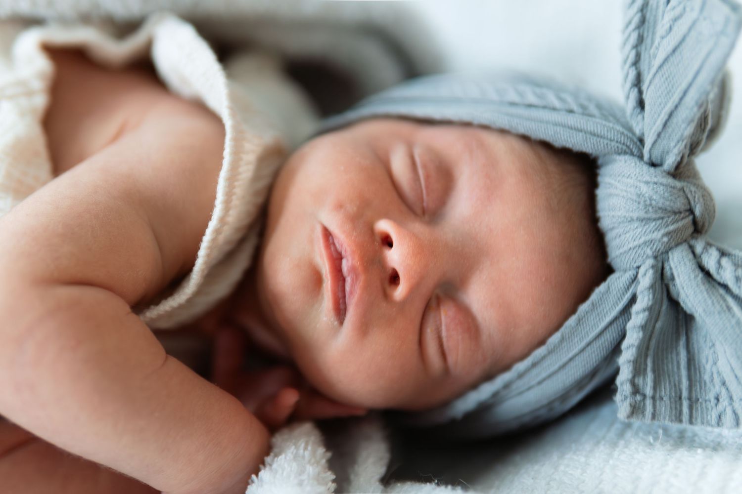 Sleeping newborn wrapped in soft gray swaddle blanket.