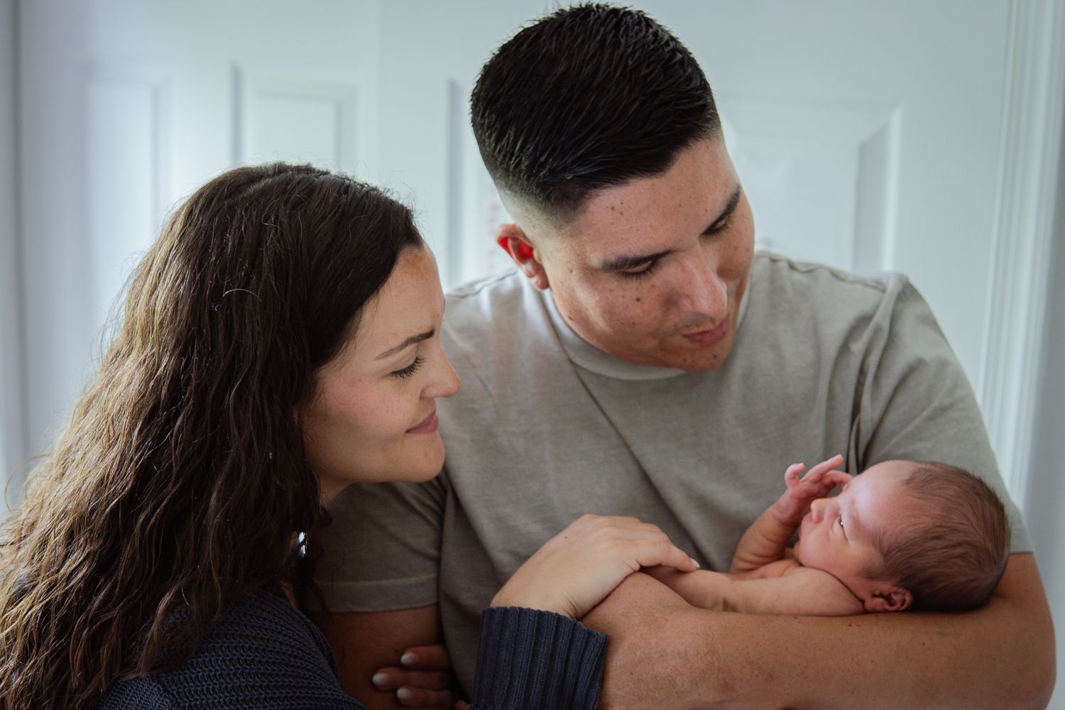 Family lifestyle photoshoot with newborn in natural window light.