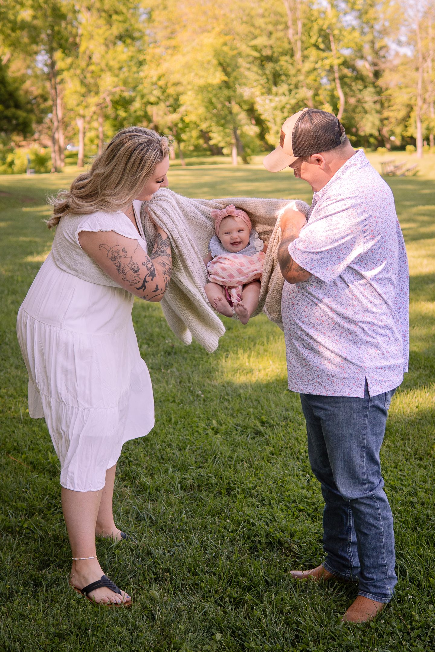 Playful family moment outdoors as parents swing child between them on a sunny day.