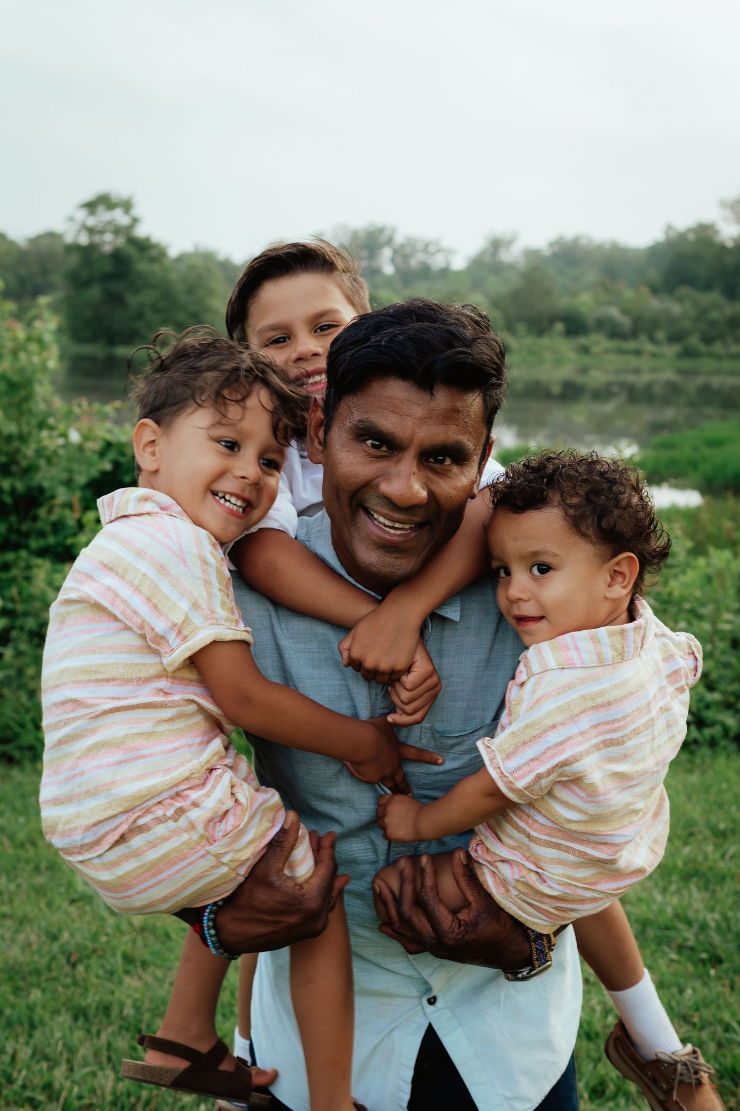 A joyful family embrace outdoors with matching outfits against a green nature backdrop.