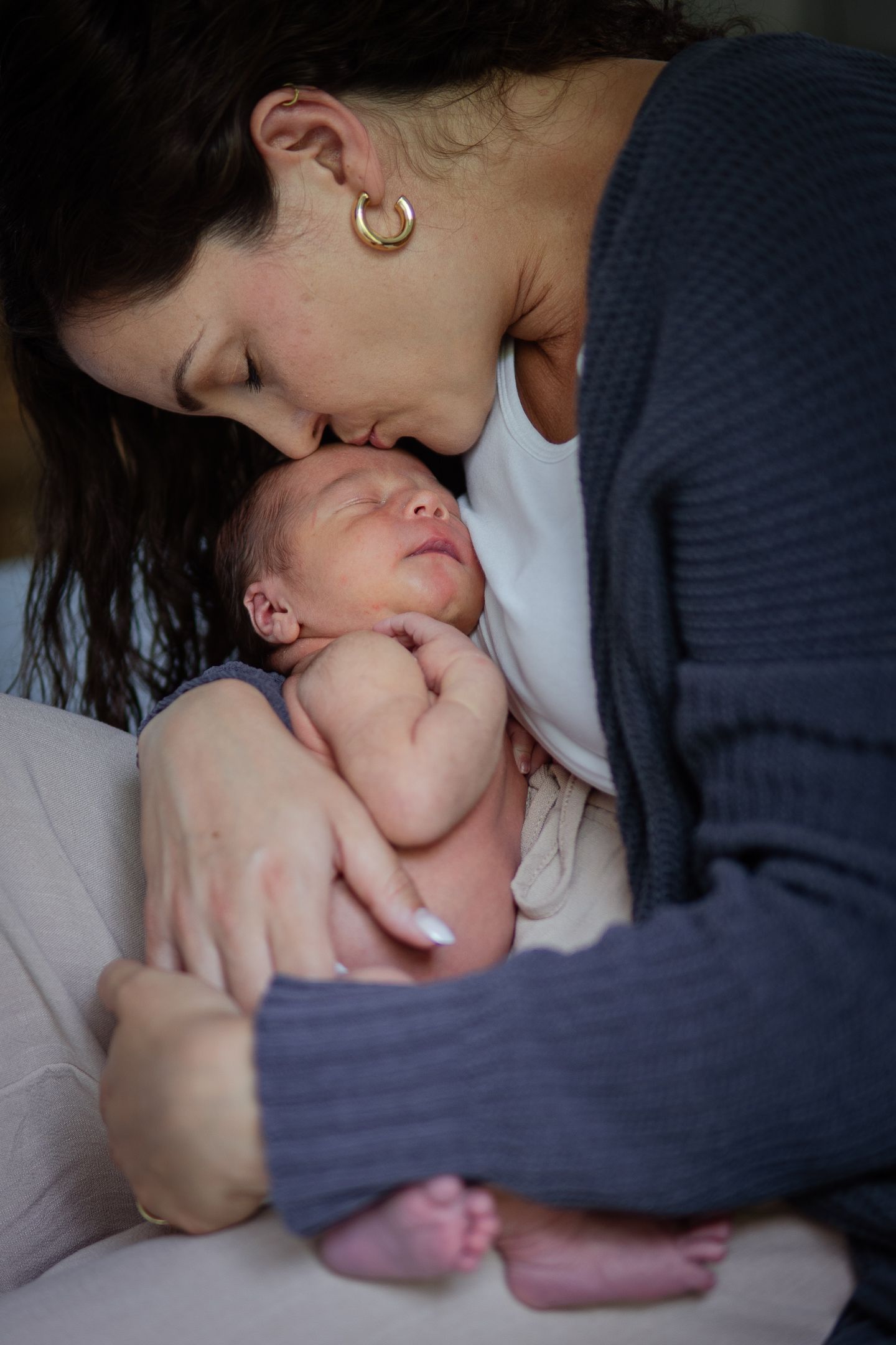 Intimate bonding moments with a newborn baby in dim lighting.