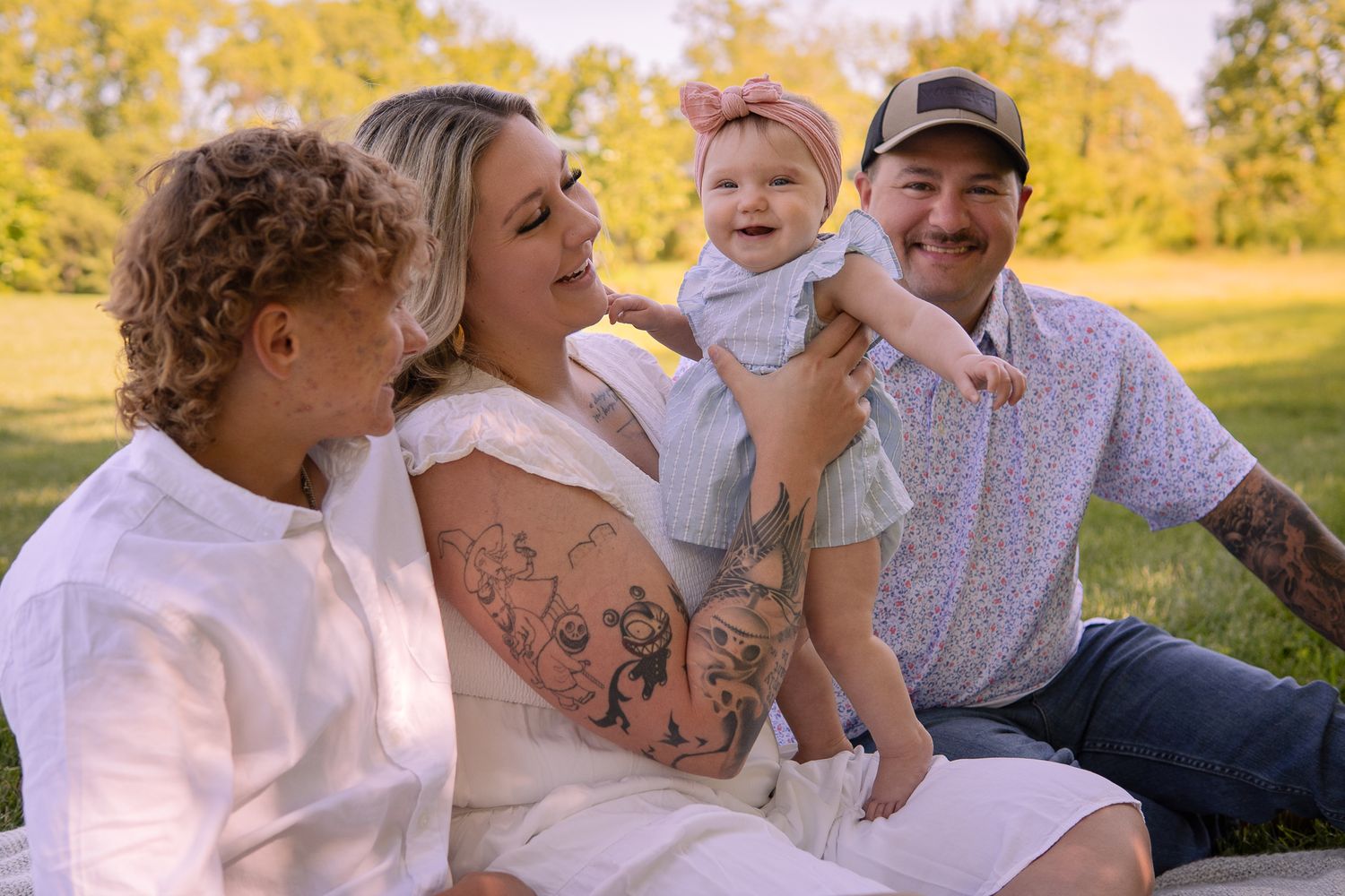 A candid family portrait taken outdoors during autumn with golden foliage in the background.