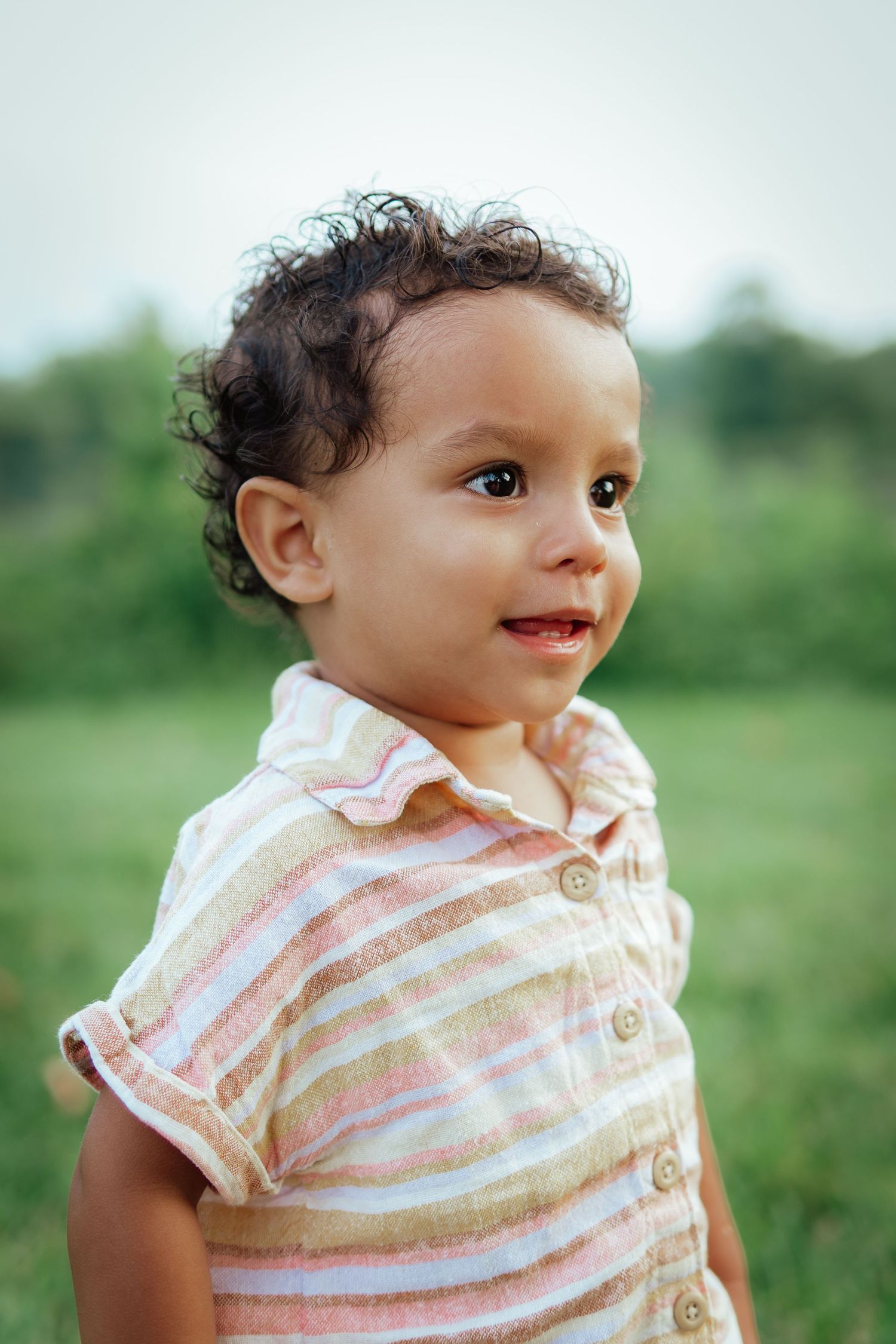 Close up portrait of young child wearing striped shirt outdoors.