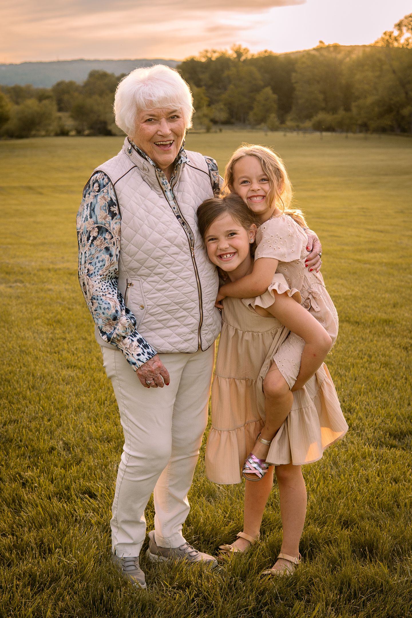 Three generations share a joyful moment together in a sunny field during golden hour.
