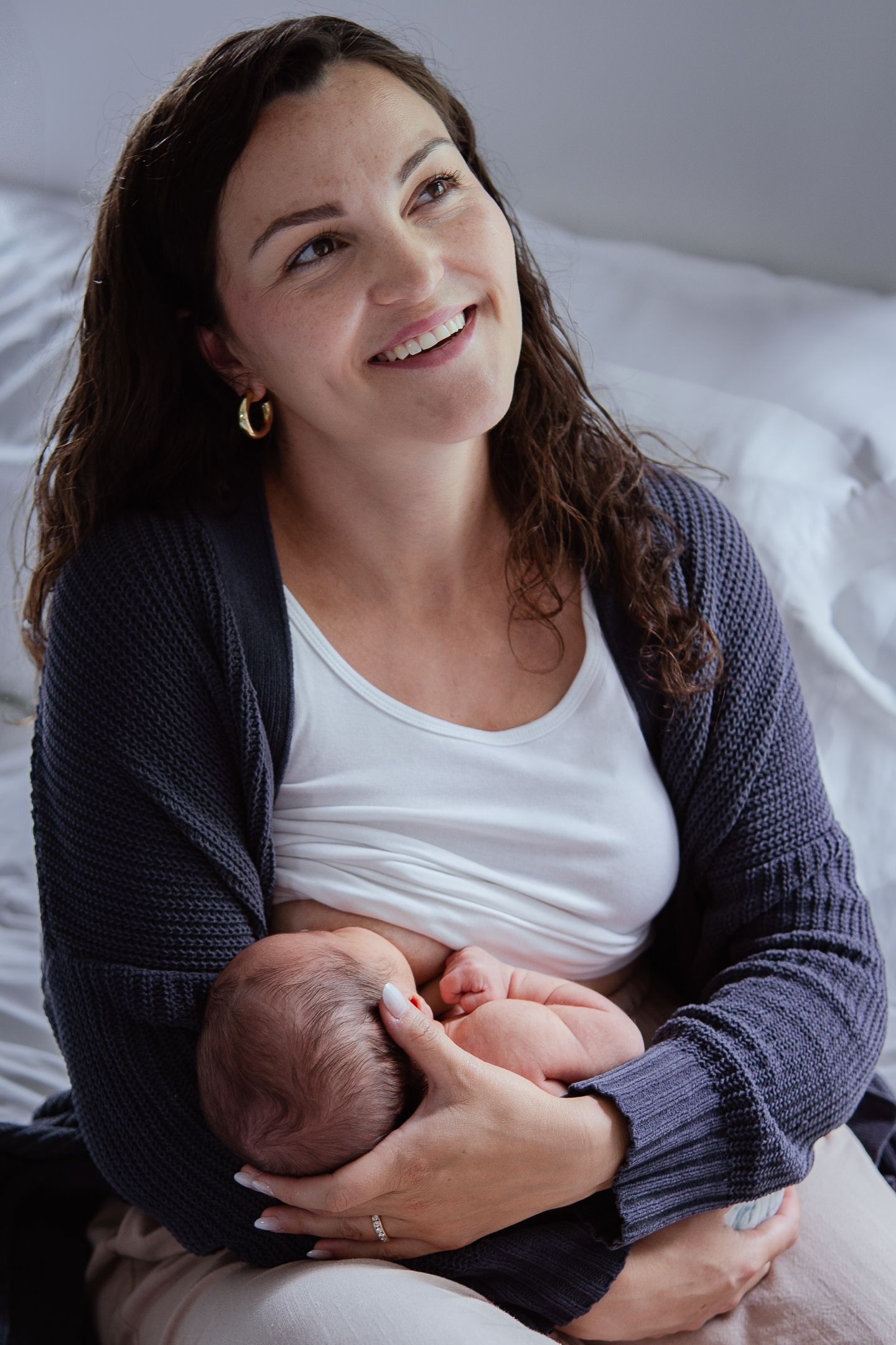 Relaxed indoor portrait session with a newborn baby and caregiver in a navy cardigan.