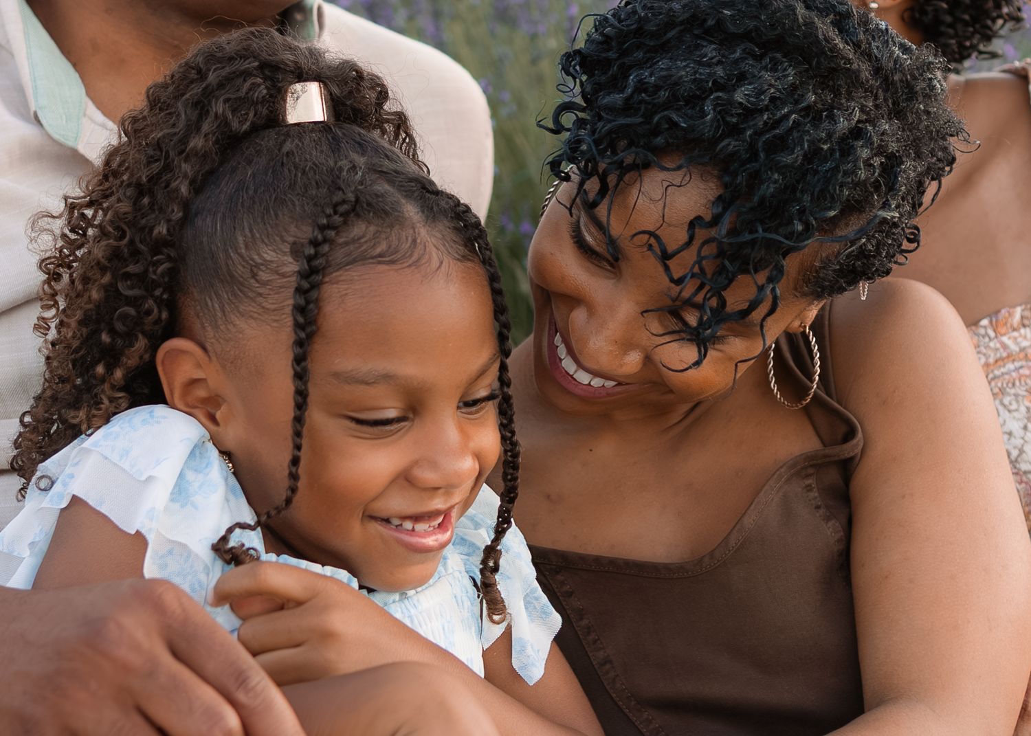 A joyful mother and young daughter share a warm, loving moment together, both smiling brightly in a heartwarming embrace.