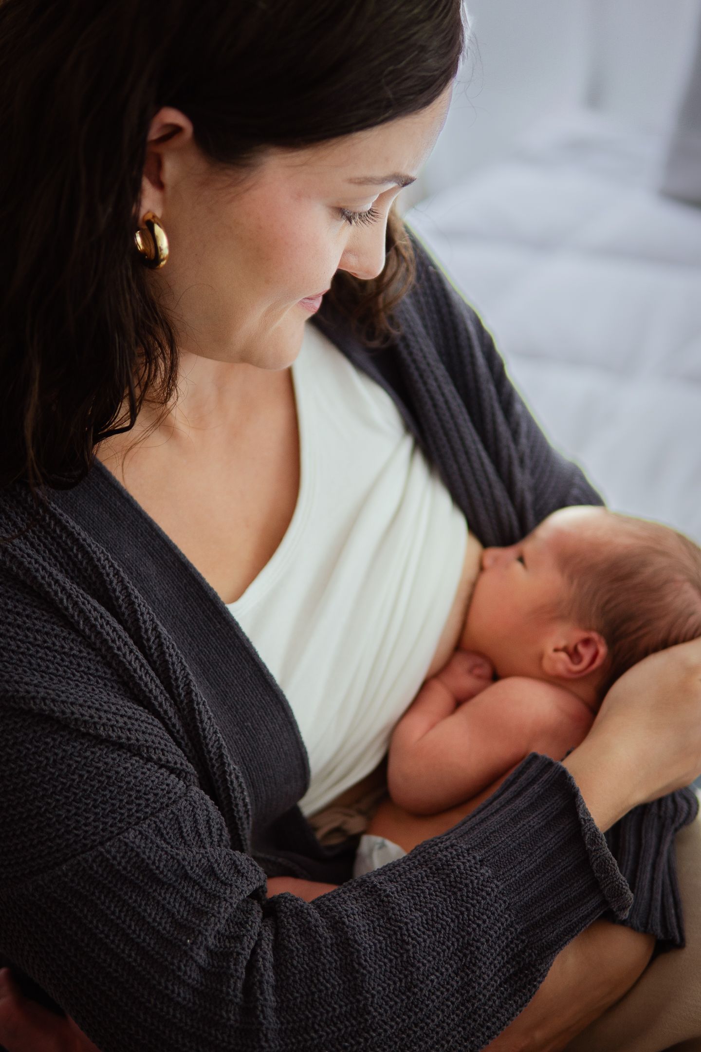 Tender nursing moment captured in soft lighting with dark sweater and white top.