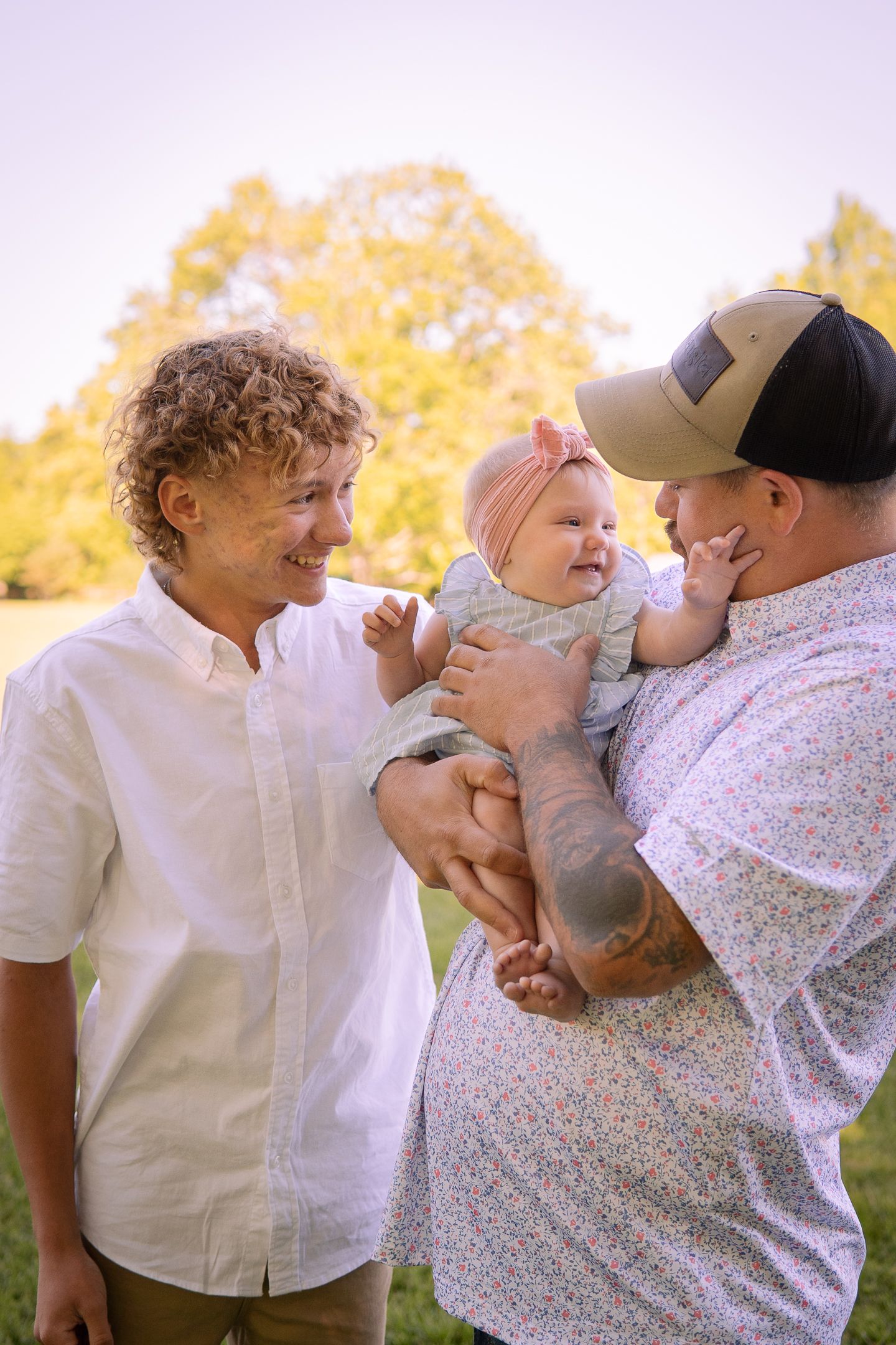 A tender family moment captured outdoors with golden fall foliage in the background.