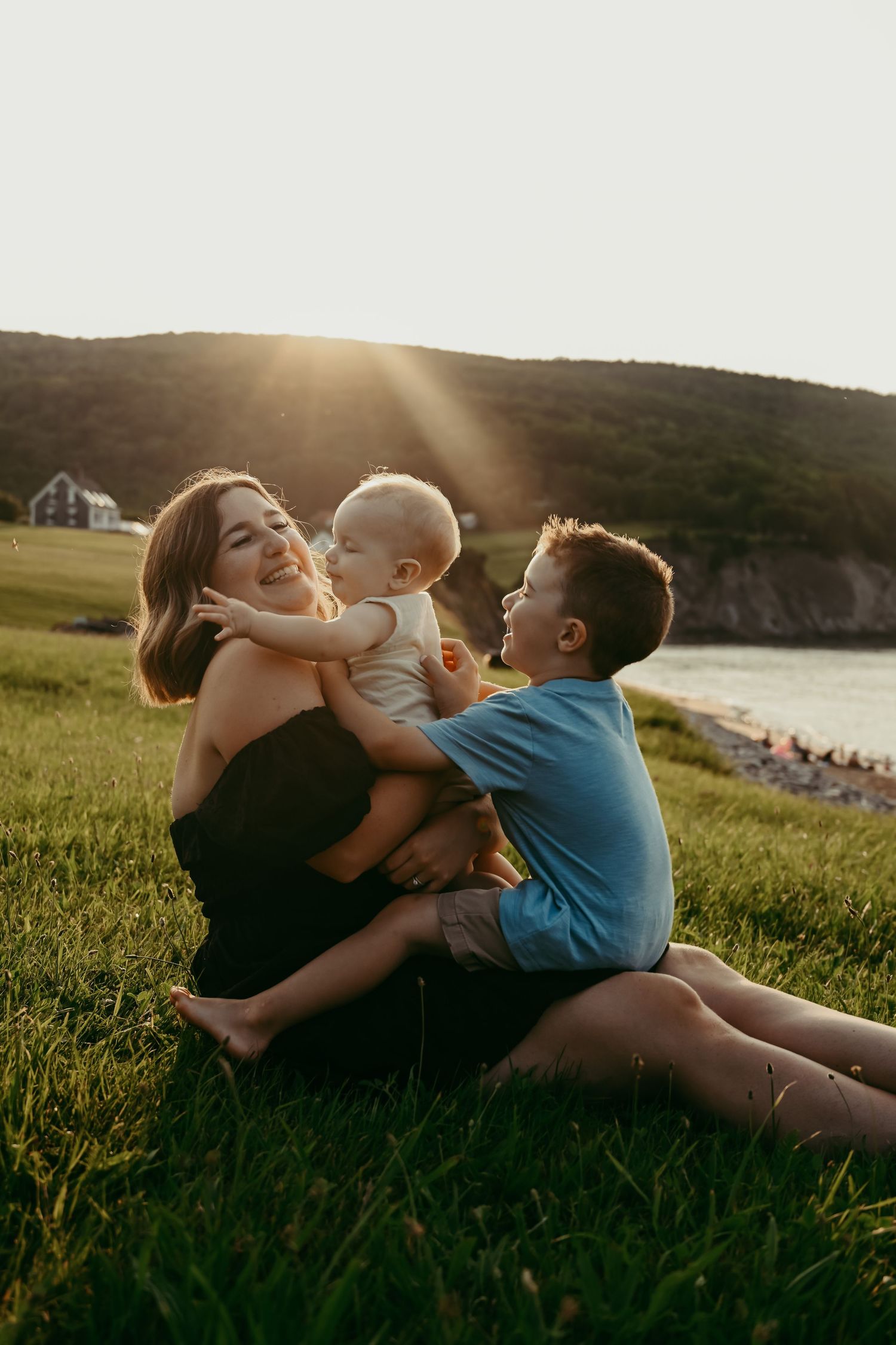 Joyful interaction on grassy hillside during sunset overlooking the coast.