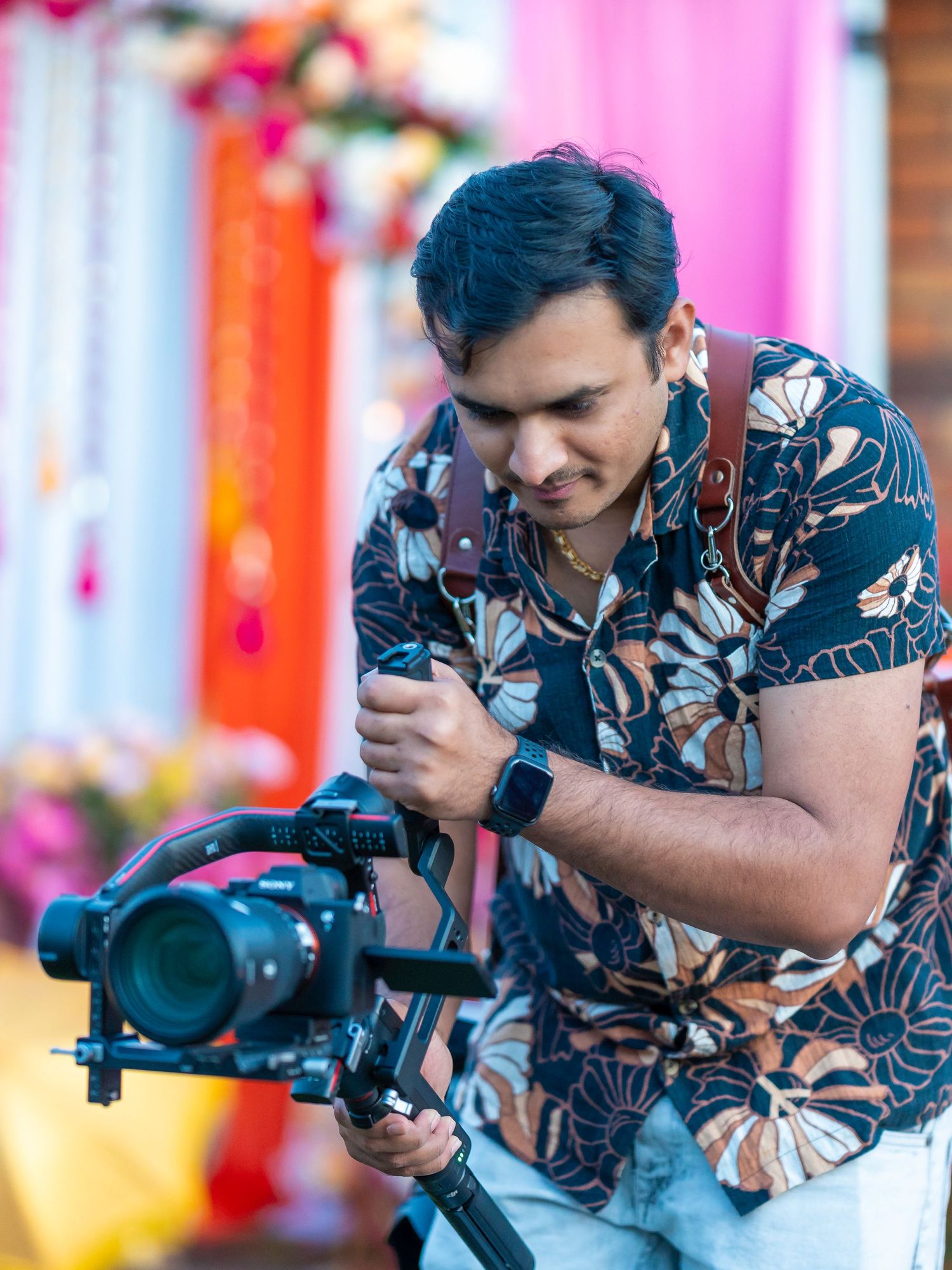 Photographer in floral shirt operating professional camera equipment at colorful event.