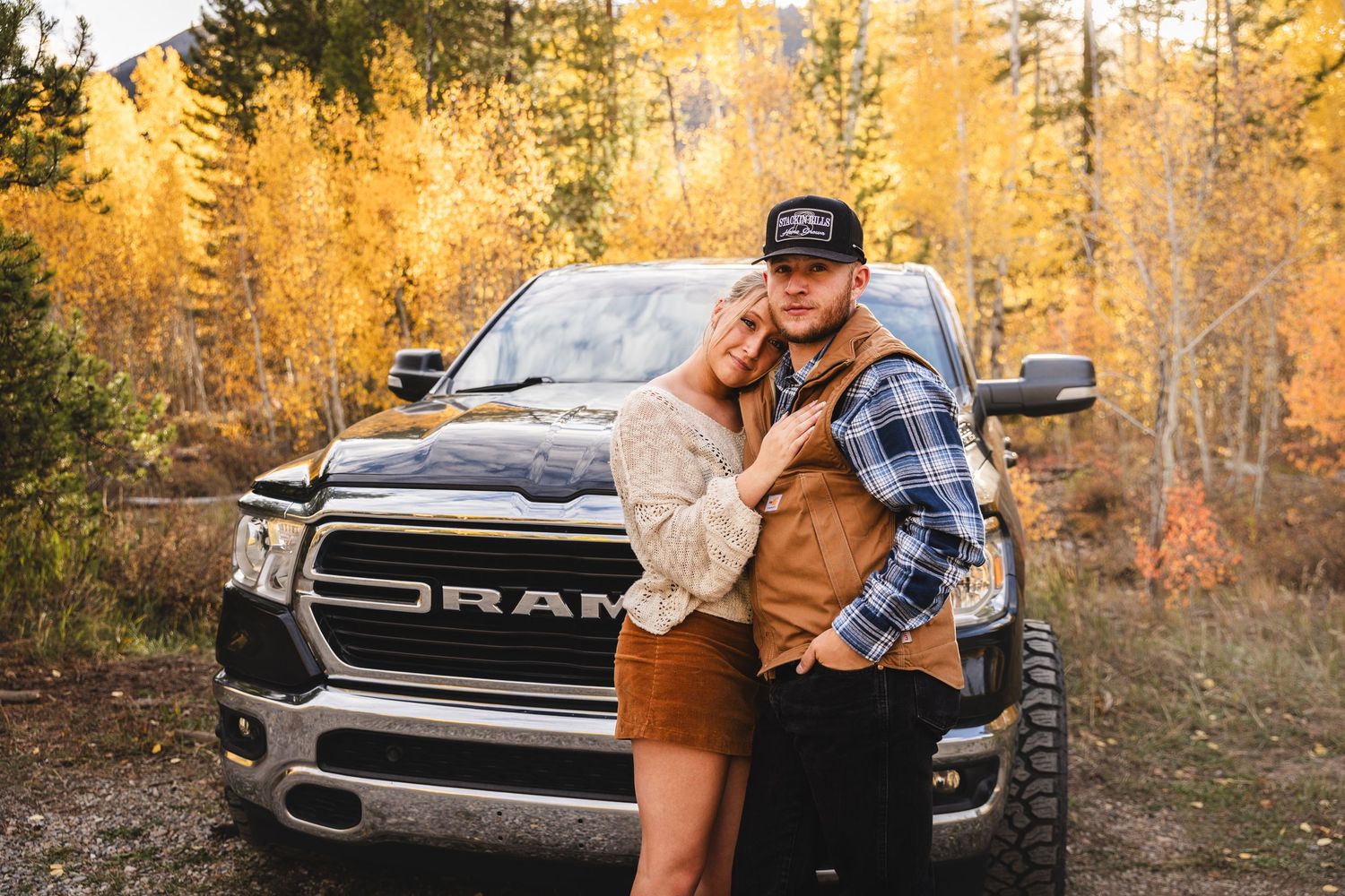 Couple embracing in front of a RAM truck surrounded by golden fall aspen trees outdoors. - couple session vail avon frisco breckenridge