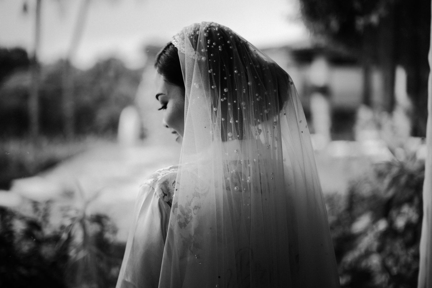 A dreamy black and white portrait of a bride wearing a long veil in soft natural light.