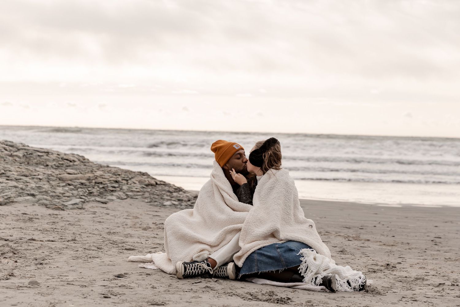 Couple enjoying a romantic moment on the beach, with the sunset and ocean creating a dreamy backdrop