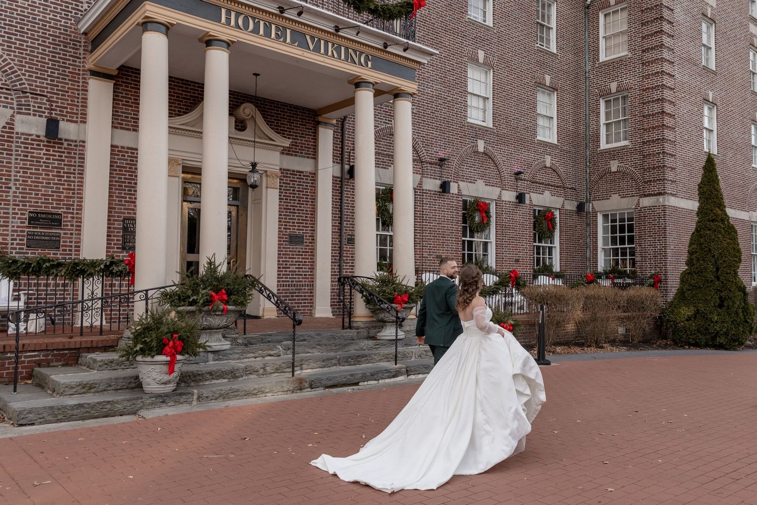 Couple in elegant wedding attire share romantic moment outside historic Hotel Bethlehem with grand brick exterior and columns.