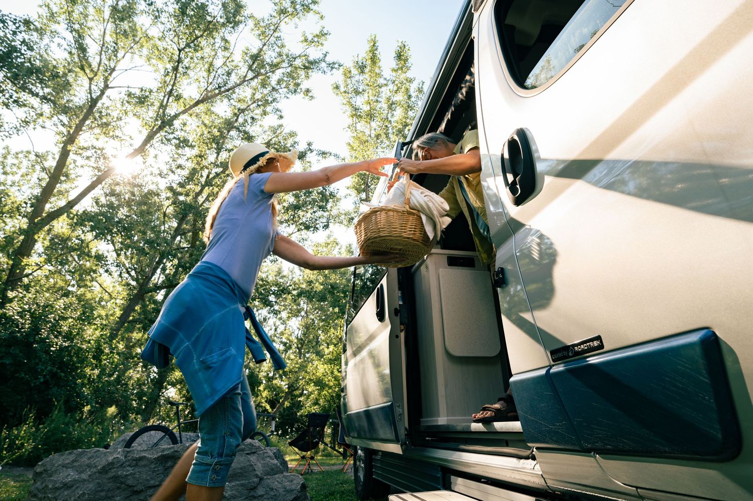 People working together to load gear onto roof of white camper van.