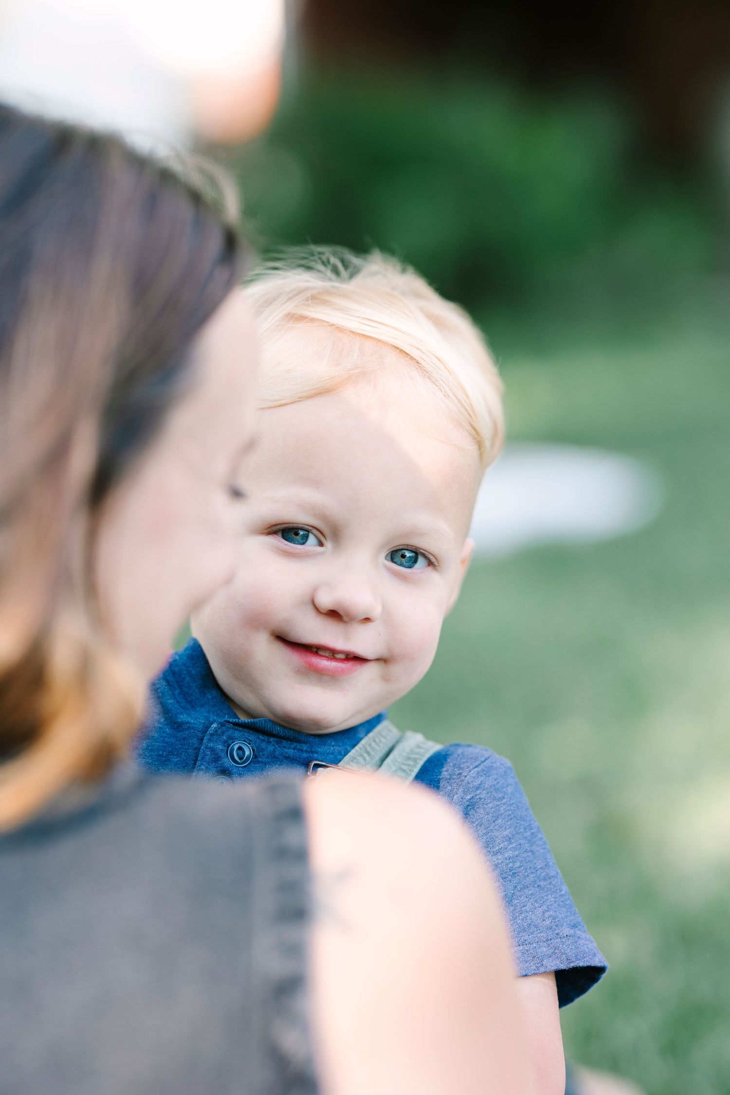 Close-up portrait showing bright smile and blue eyes against blurred background.