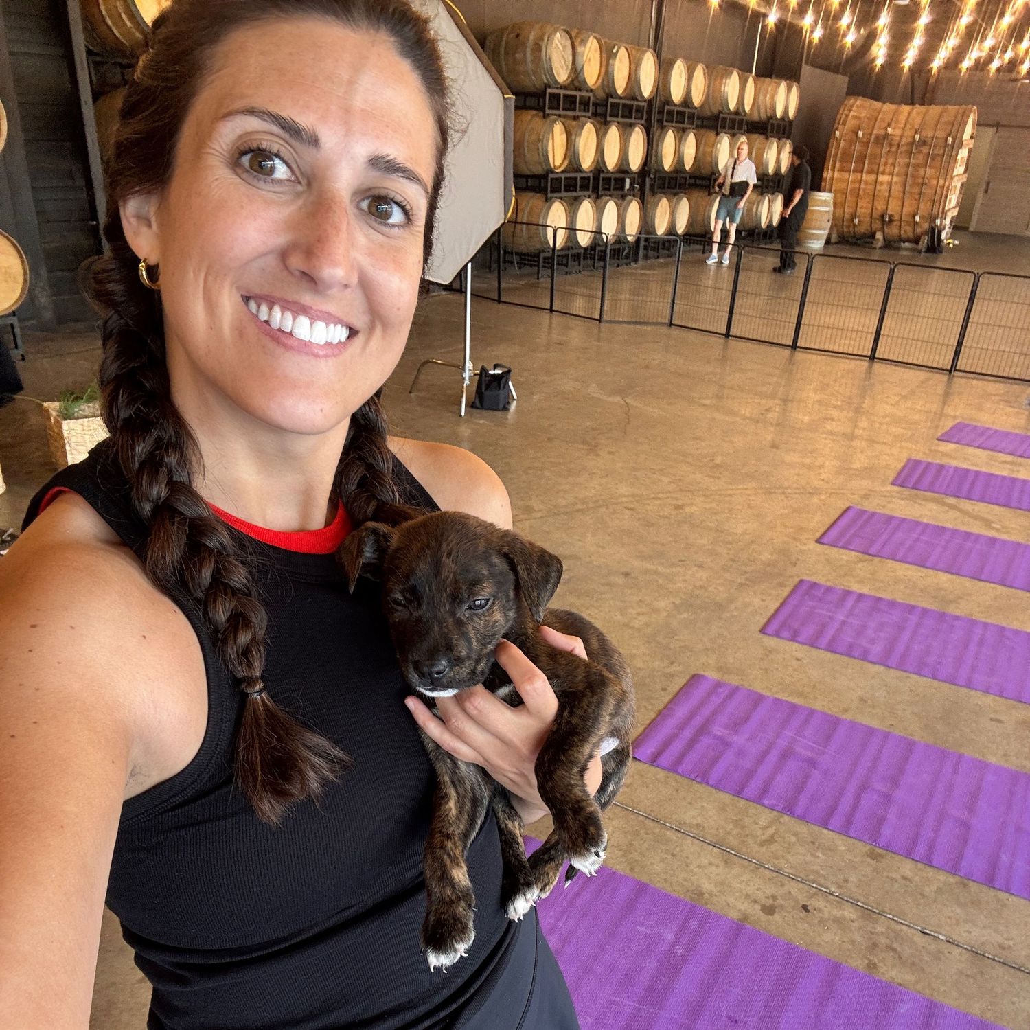 Pet photographer taking a selfie while volunteering and holding a small puppy at a puppy yoga event
