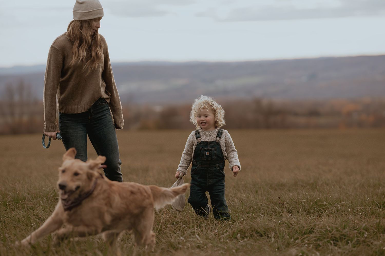 Dog and companions share a joyful moment in a scenic autumn field.