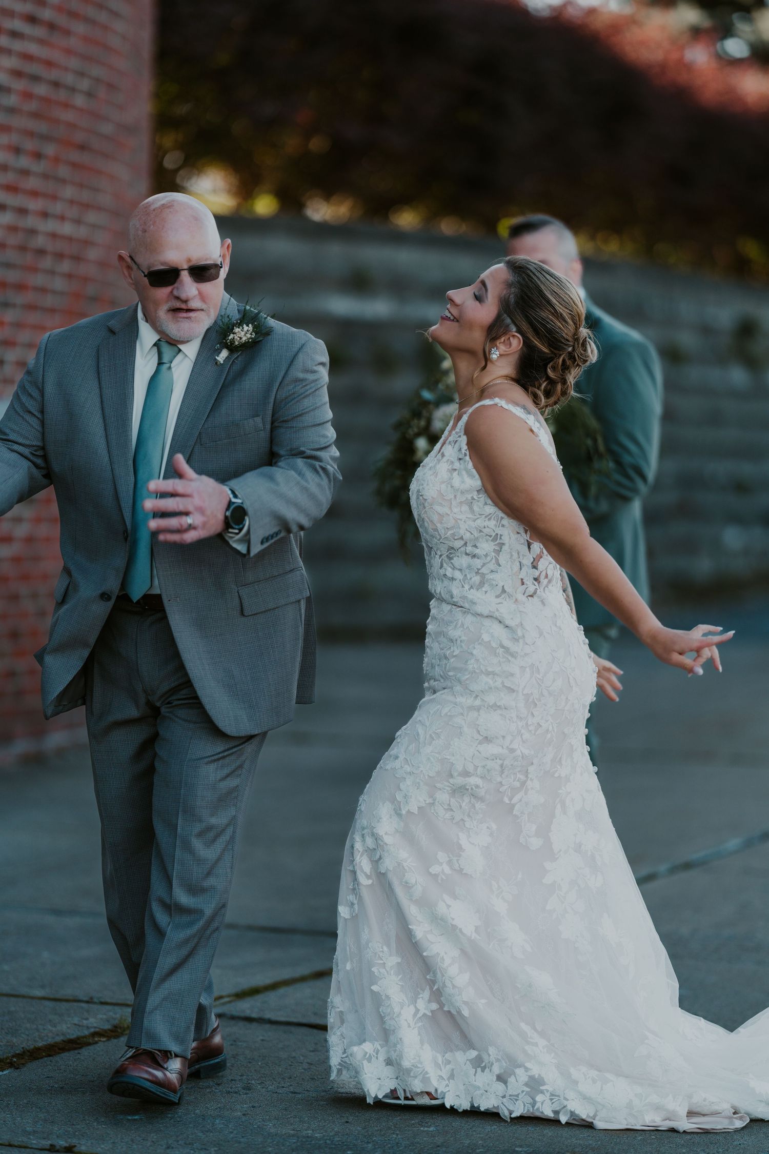 Wedding couple performing a dramatic dip pose against a brick wall backdrop.