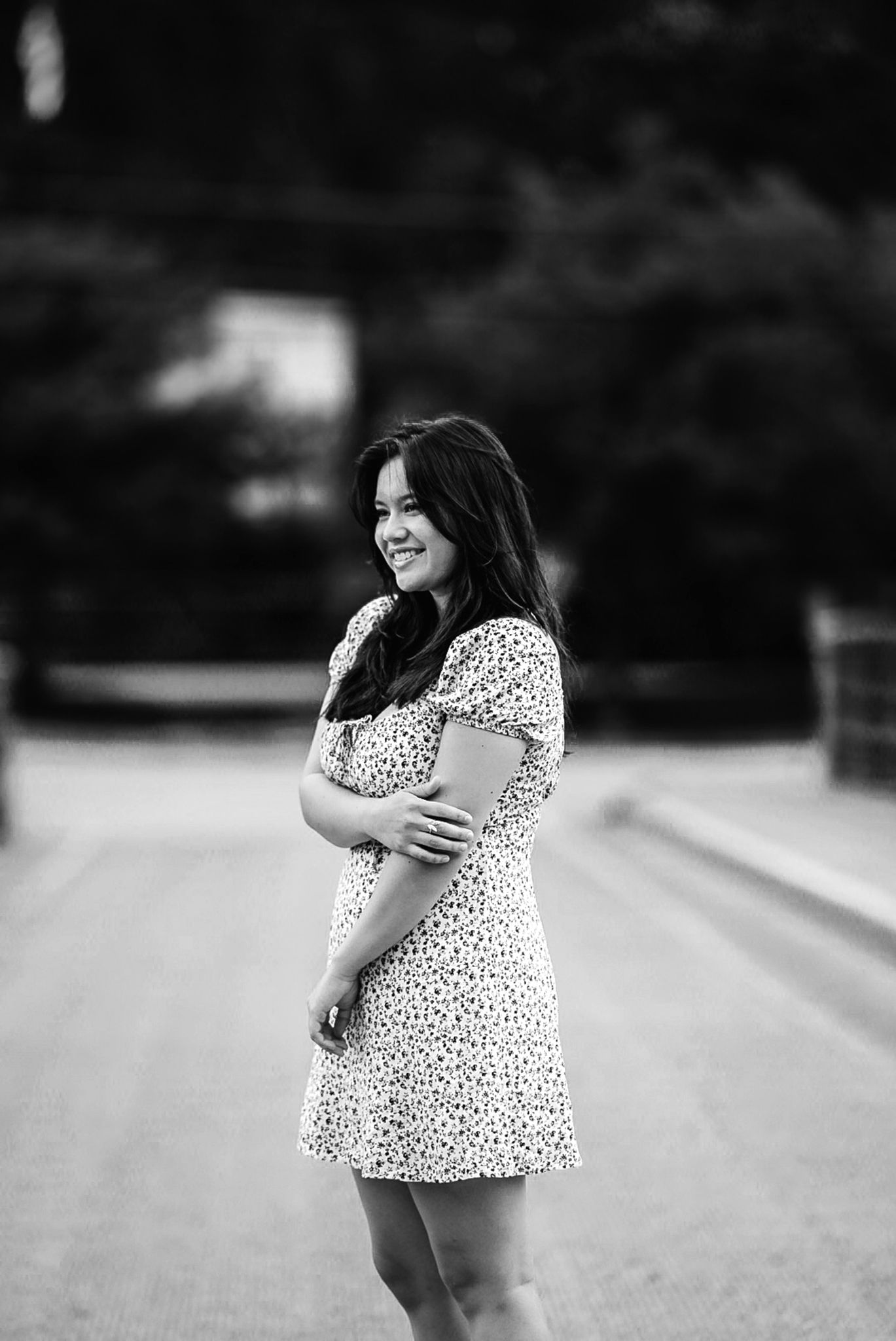A black and white portrait shows someone in a polka dot dress posing outdoors.