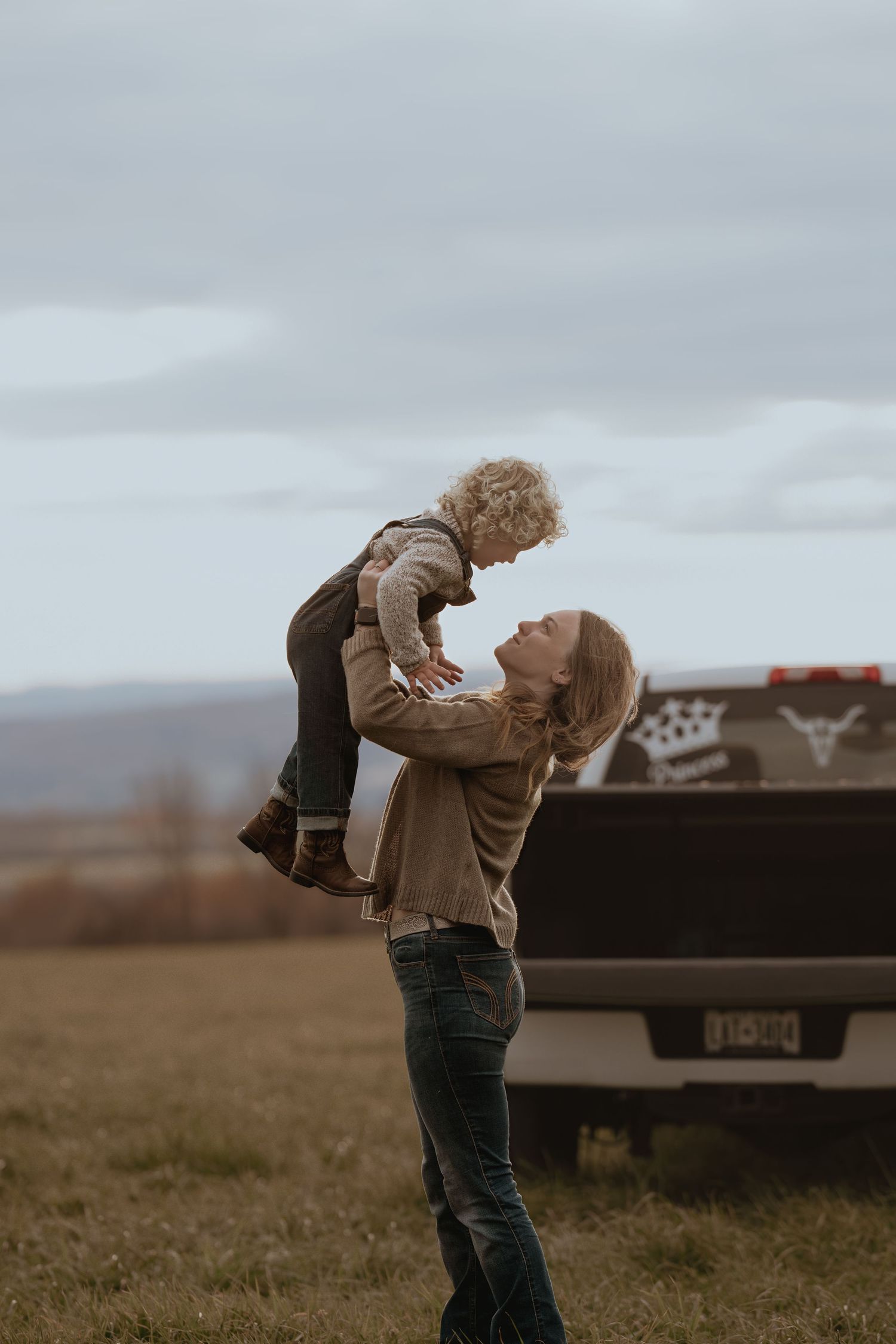 Heartwarming playtime captured in front of a pickup truck on a cloudy day.