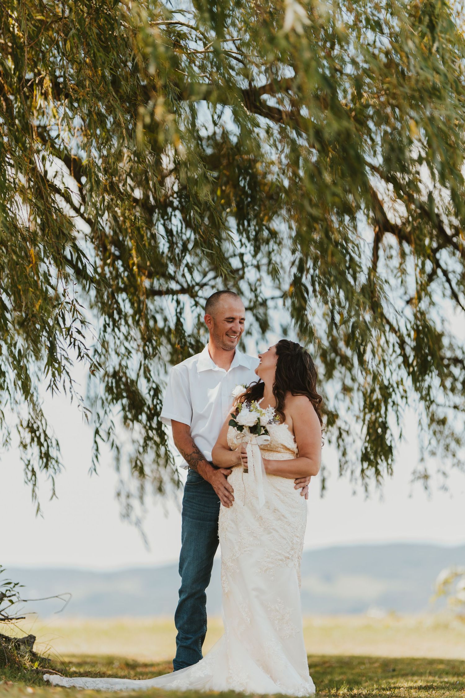 Joyful wedding portraits under weeping willow trees in natural light.