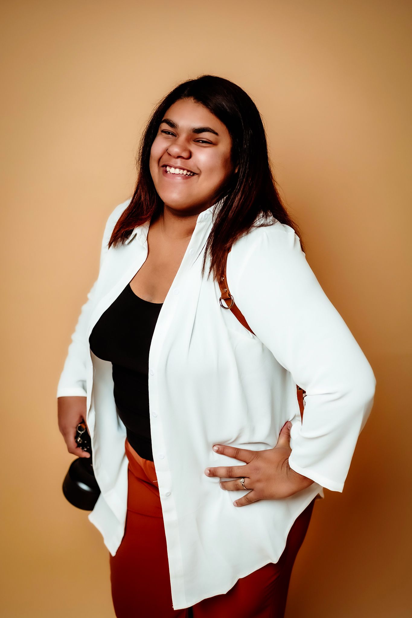 Professional studio portraits showing fashionable white blazer against warm brown backdrop.