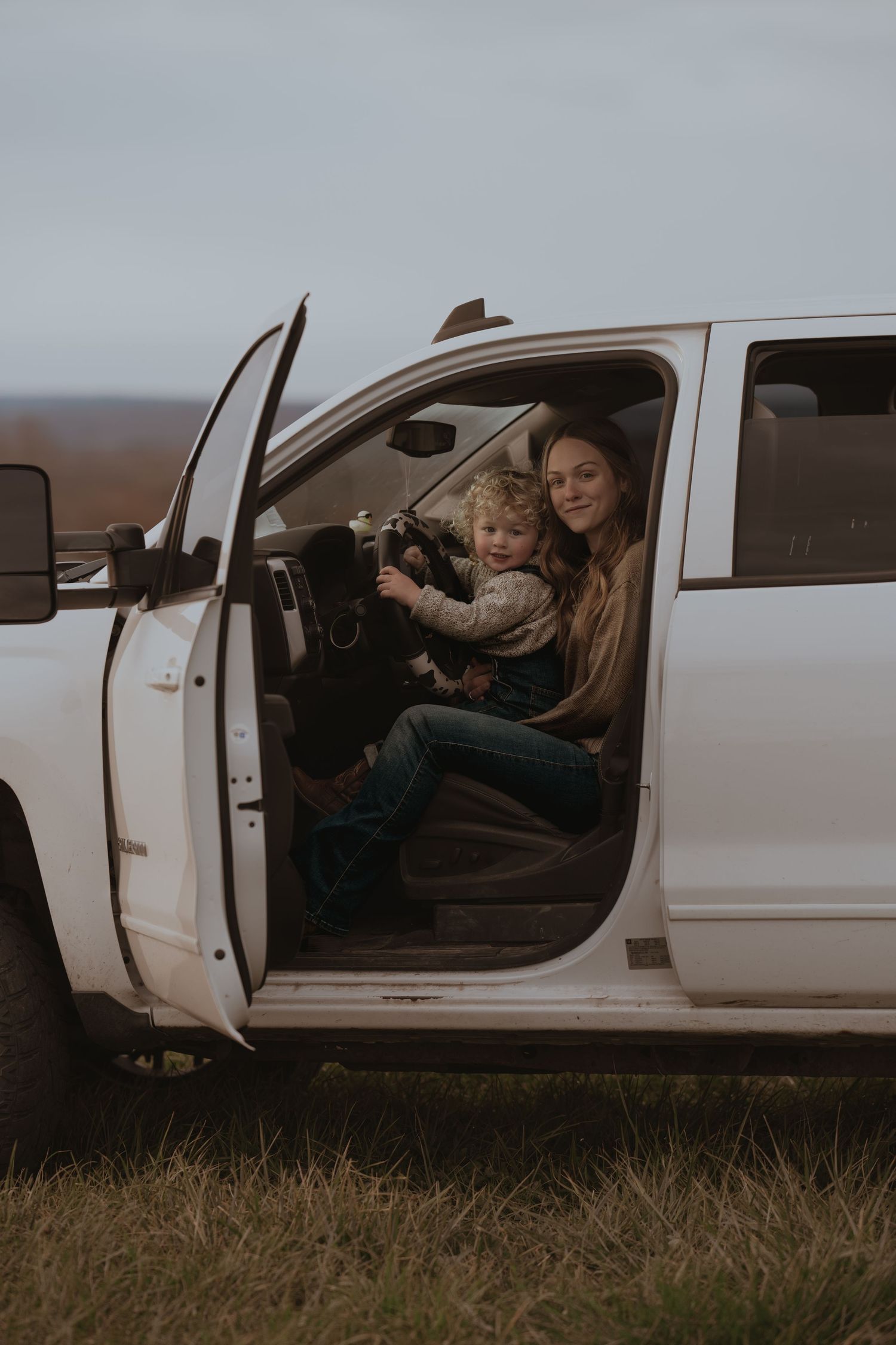 Fun moments shared inside a white pickup truck on a cloudy afternoon.