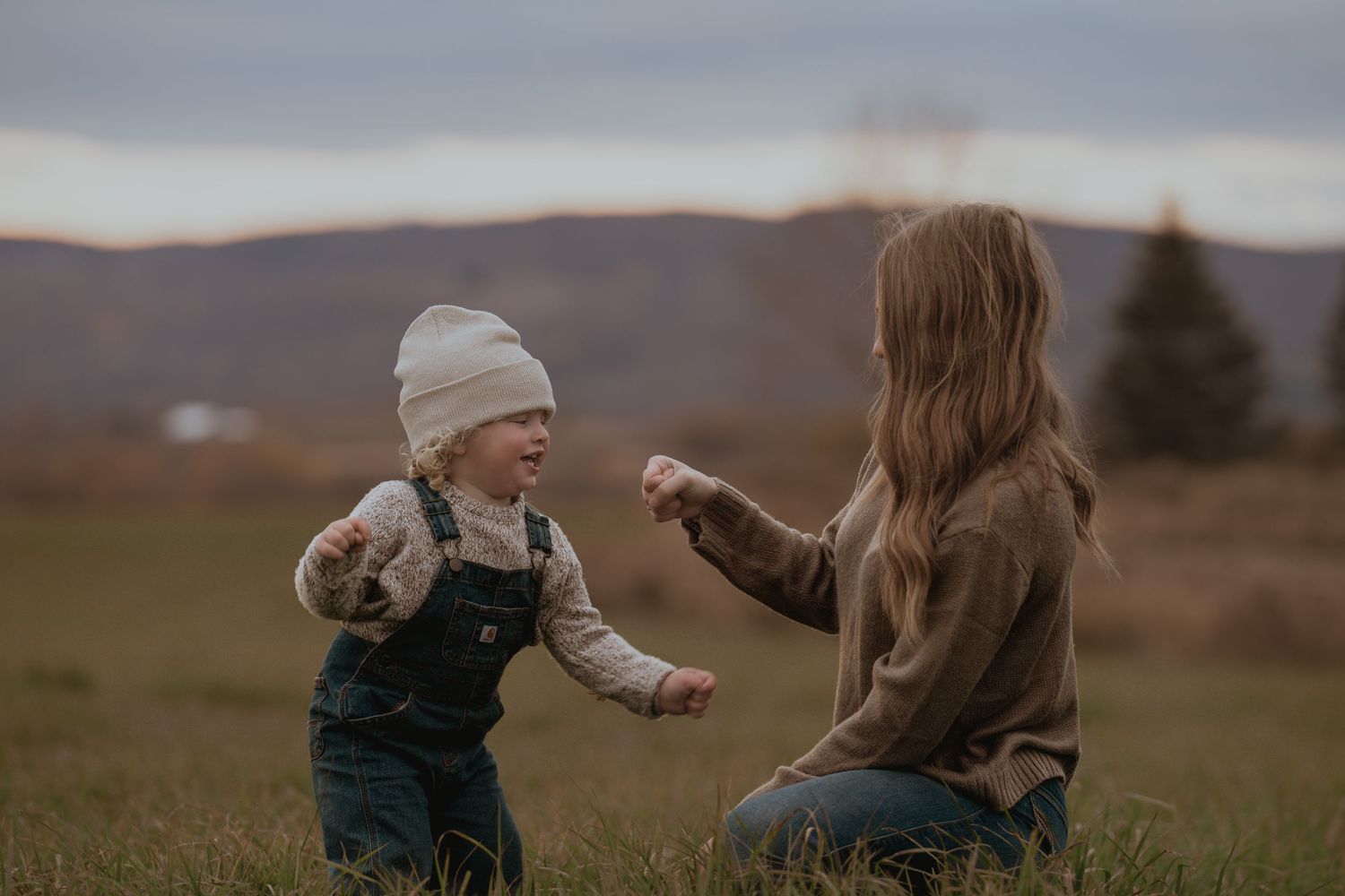 Parent and child share joyful moments outdoors against a moody sky backdrop.