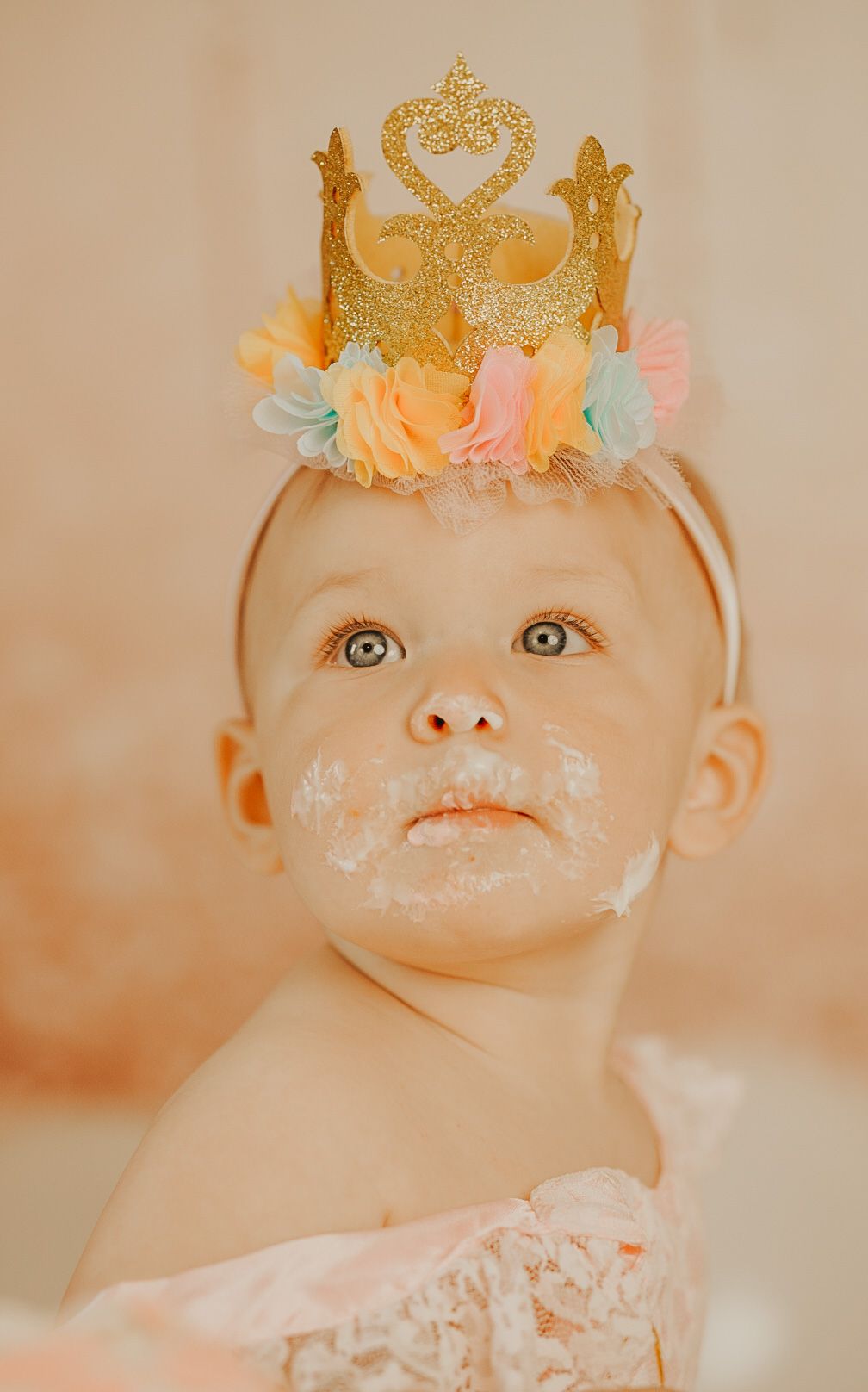 Close-up shots of baby wearing gold crown with various expressions against neutral background.
