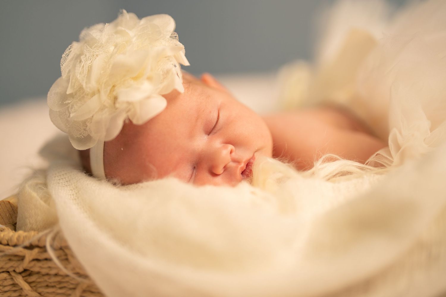Artistic portrait of a sleeping newborn surrounded by soft white fabric.