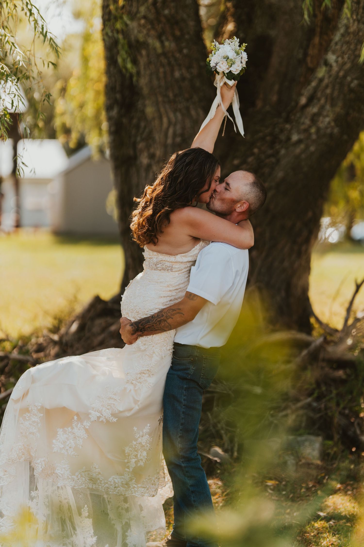 A romantic couple embraces near an autumn tree during an outdoor photoshoot.