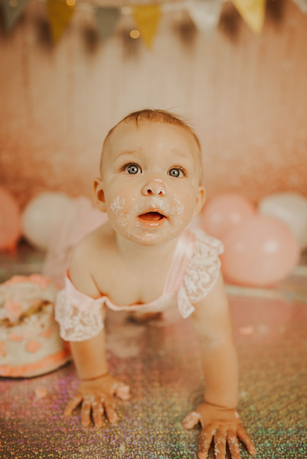 A sequence of photos capturing a small child in white lace crawling on a glittery surface.