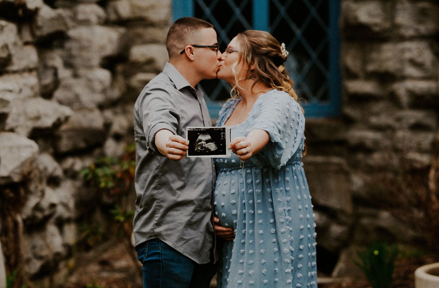 Romantic couple portrait session featuring textured blue dress against stone wall background.