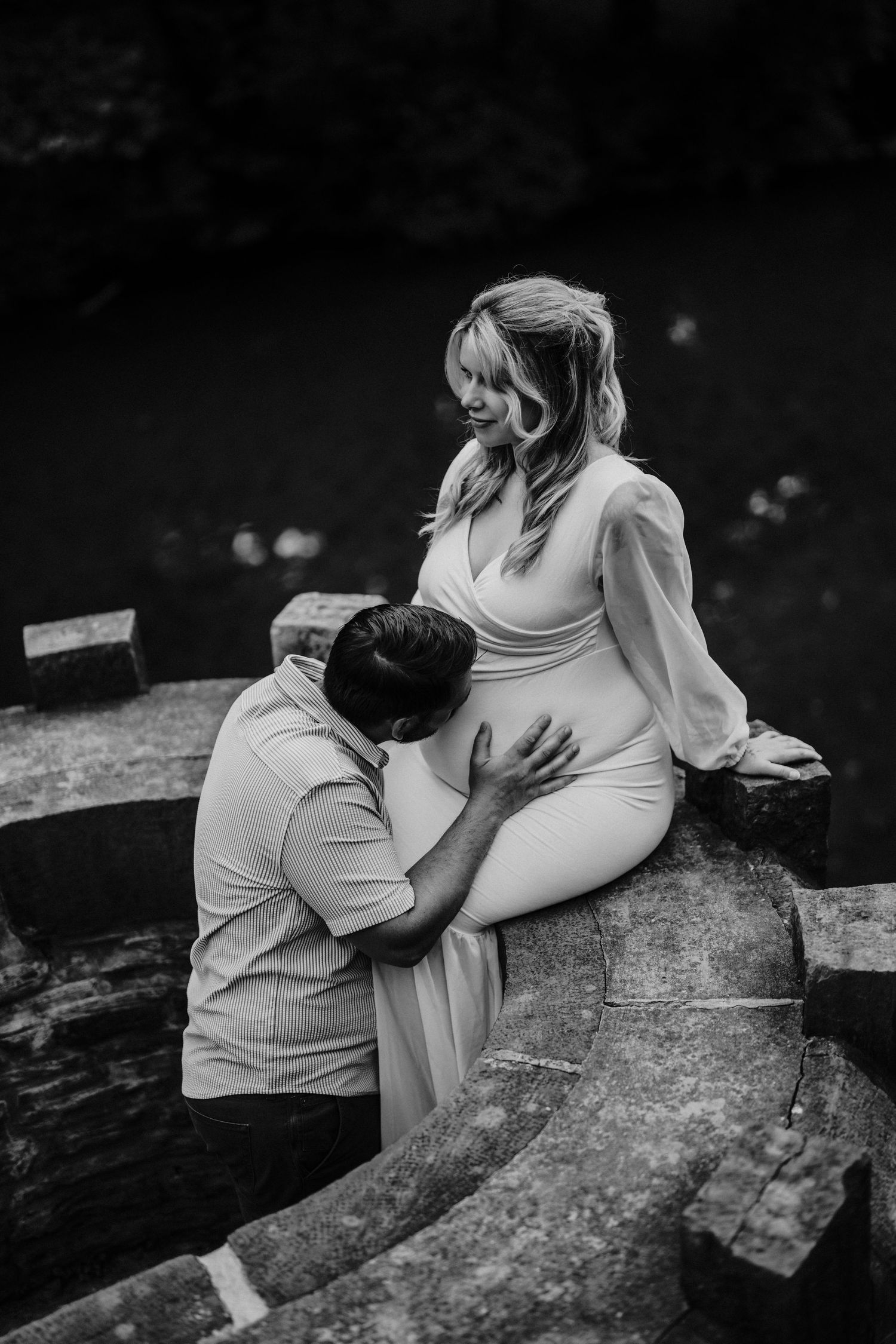 Black and white photo of a couple sharing an intimate moment together on a stone surface.