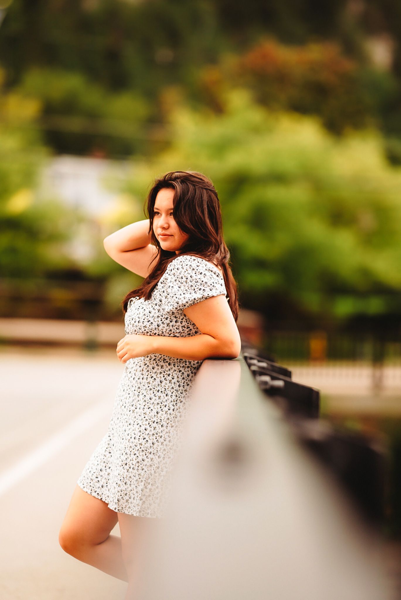 A polka dot dress is worn against a blurred floral garden background in warm lighting.
