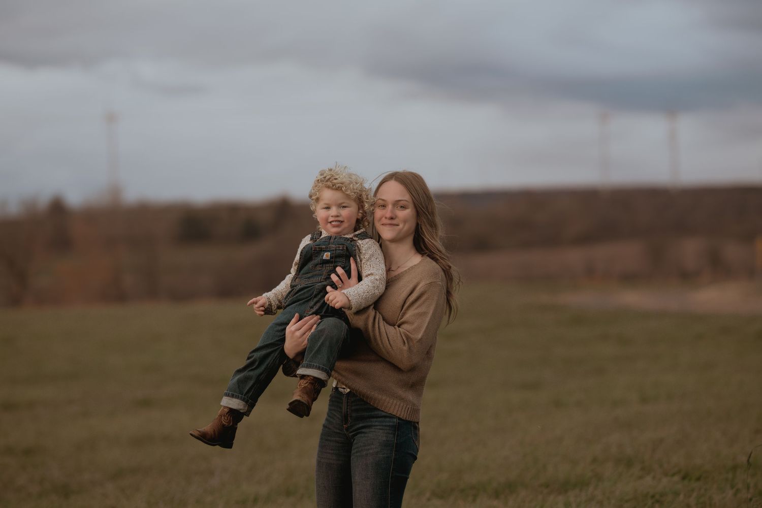 A family plays together in a grassy field during golden hour with mountains in the background.