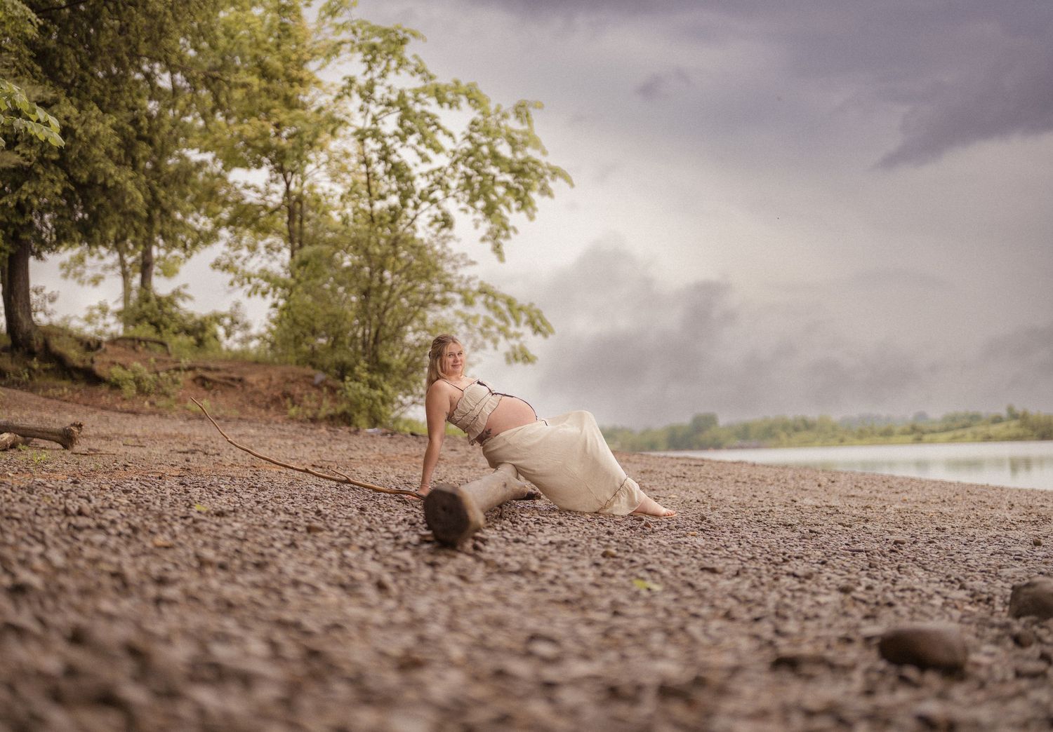Artistic low-angle shot of someone reclining on pebbled beach near water.