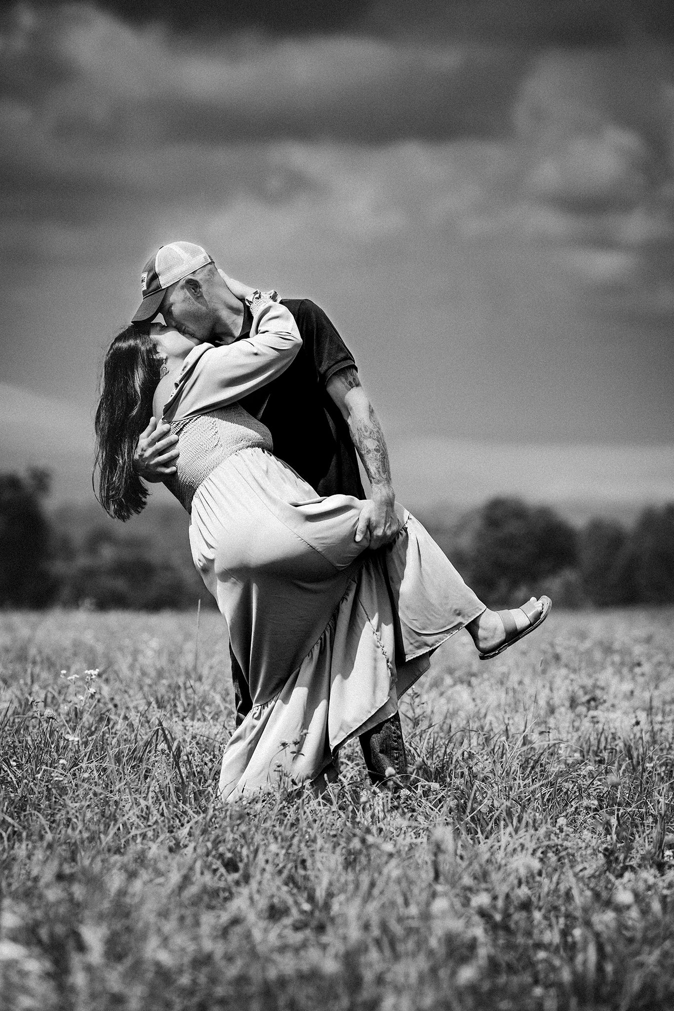 Romantic black and white portrait of couple dancing in meadow.